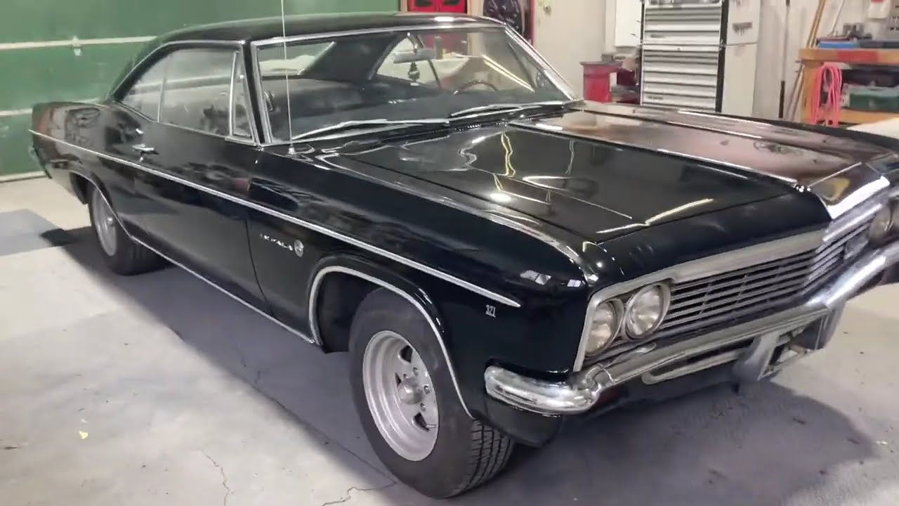 Restored 1966 Chevrolet Impala in gloss black parked inside the Jack's Custom Restoration shop