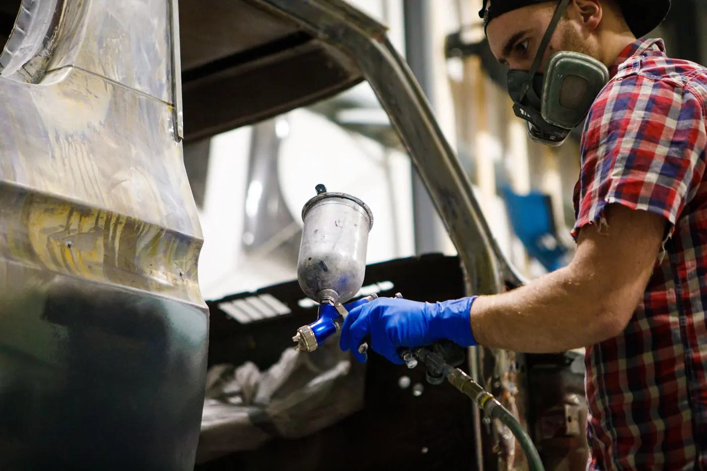 Painter spraying a stripped panel in the booth at Jack's Custom Restoration