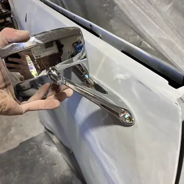 New chrome side mirror held up to a freshly prepped door