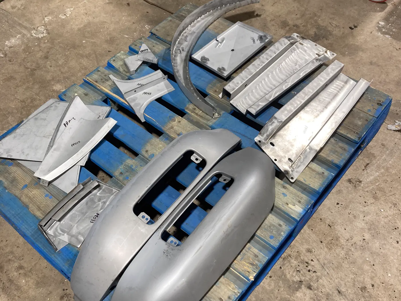 New replacement sheet metal and patch panels laid out on a pallet at Jack's Custom Restoration