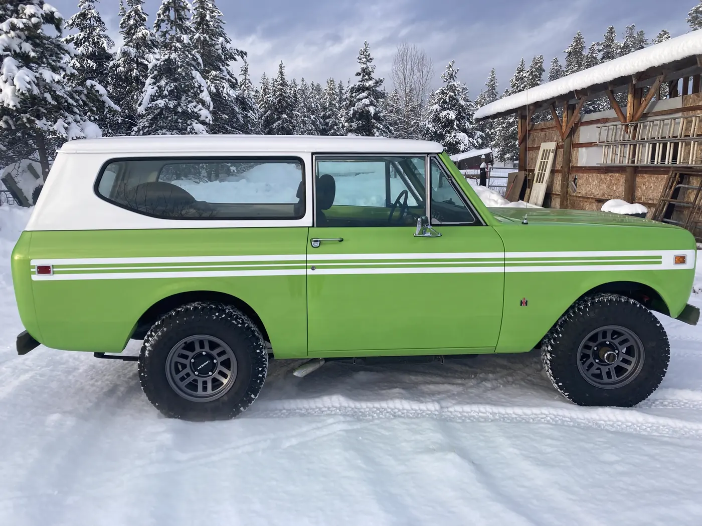 International Scout II restored in green and white, side profile in the snow outside Jack's Custom Restoration