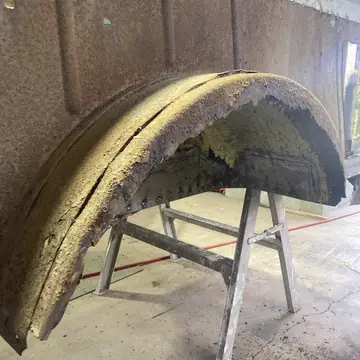 Rotted inner wheel tub on a stand before the rust is cut out